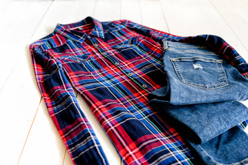 Clothes concept. Checkered shirt and jeans on wooden background. Side view