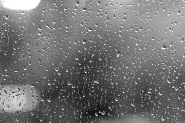 Raindrops on glass in rainy weather close up. Natural background black and white