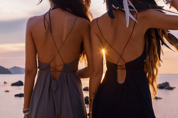 silhouette of two young beautiful girls having fun on the beach at sunset