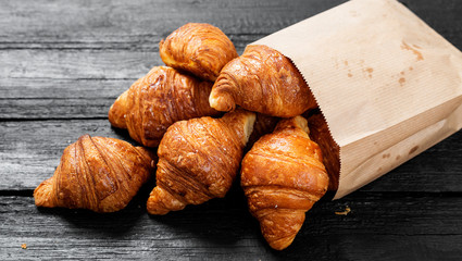 Freshly baked croissants on black wooden table, top view.