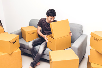 Happy young man unpacking box and moving into their new home.House moving and real estate concept