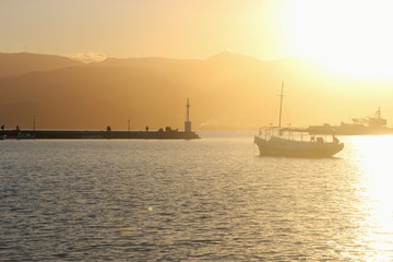 Obraz premium Sunset above the mediterranean sea. In the bay of Nafplio. Peloponnese, Greece. Mole and lighthouse of Nafplio and boat. South-east Europe.