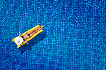 Enjoying suntan. Vacation concept. Top view of slim young woman in bikini on the yellow air...