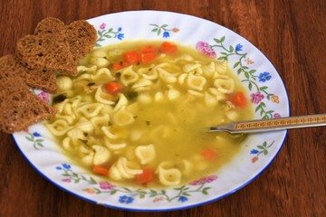pasta soup with carrots and pieces of white and black bread