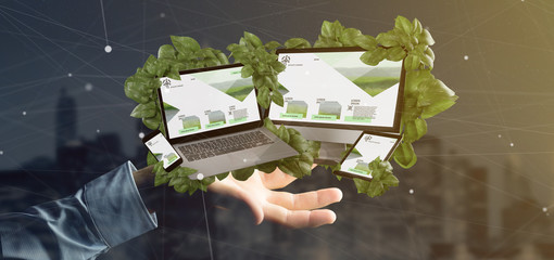 Businessman holding a Connected devices surrounding by leaves 3d rendering