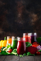 Colorful vegetable juices and smoothies from tomato, carrot, pepper, cabbage, spinach, beetroot in bottles on kitchen table, vegan food and drink, selective focus