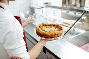 Salesman holding fresh baked pie at the pastry shop, close-up view