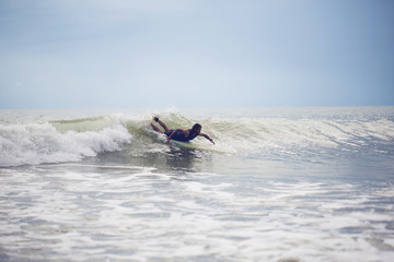 Mixed race Surfer paddling with longboard on small wave