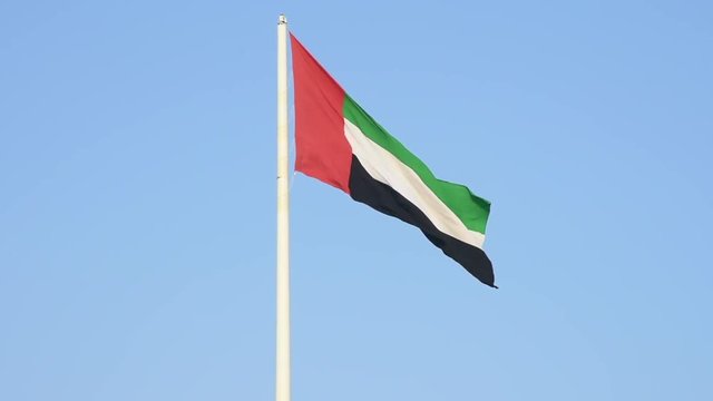 United Arab Emirates Flag flying and waving in the sunshine with a deep blue sky background.