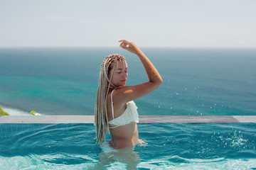 Woman enjoying  in swimming pool with sea background view