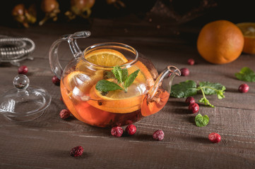 Glass teapot with herbal tea, orange and mint