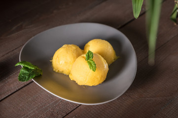 Mango ice cream sorbet with mint leaves on rustic background