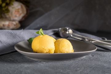 Mango ice cream sorbet with mint leaves on rustic background