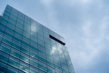Low Angle Of Modern Glass Skyscraper Against Vivid Blue Sky with Clouds