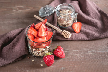Glass of oatmeal muesli with strawberry, granola and honey