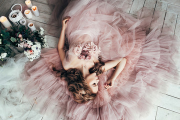 beautiful blond woman lies on a wooden white floor in a beautiful soft pink dress vintage style