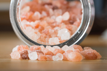 Himalayan pink rock salt in a bottle container on a wooden surface.  - Powered by Adobe