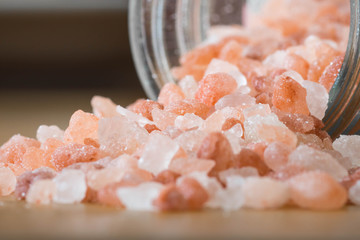 Himalayan pink rock salt in a bottle container on a wooden surface.  - Powered by Adobe