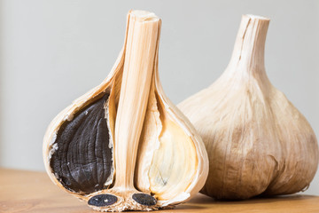 Black garlic - made from fresh garlic and fermented. It is odorless and very healthy Asian food ingredient. Close up shot with cloves and whole garlic. 