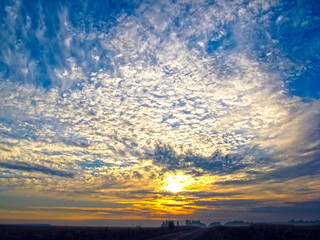 Autumn sunrise with fog. The sun's rays of the morning sun break through the clouds against the blue sky.
