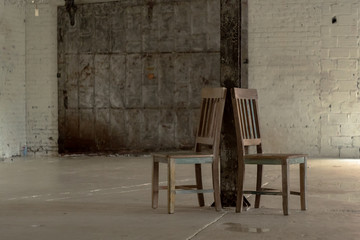 Two Wooden Chairs Against A Wooden Beam In An Empty Warehouse