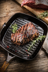 Grilled beef steak in grill pan with herbs rosemary on wooden table