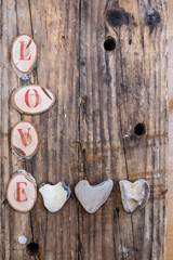 Schriftzug Love,herzformige steine,hölzerner hintergrund