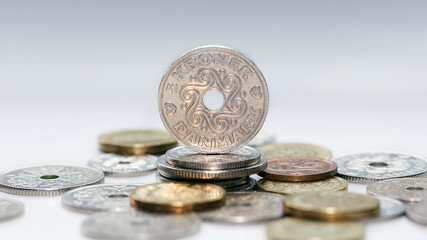 Five kroner coin standing on a pile of other Danish coins with selective focus. The krone is the official currency of Denmark, Greenland, and the Faroe Islands, introduced on 1 January 1875.