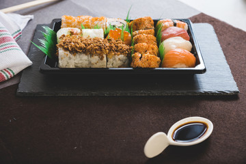 Eating sushi. Japanese food restaurant, unagi and salmon sushi on dark background. Taking piece with chopsticks. Closeup on black wood
