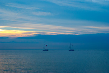 Fototapeta premium Yachts in the sea against the sunset sky