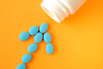 The tablets form an arrow pointing to an empty jar . Symbolic image. A bunch of blue pills on an orange background. The concept of pharmacology. The correct treatment concept.