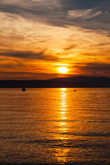 Obraz premium Orange sunset on the sea with the sun, a beautiful sky on the background of mountains
