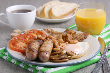 Classic English breakfast served: eggs, bacon, beans, juice and tea
