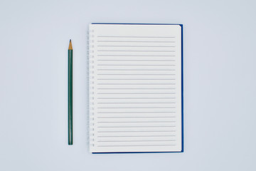 First blank page of note-taking book and pencil for writing text and ideas isolated on the white background