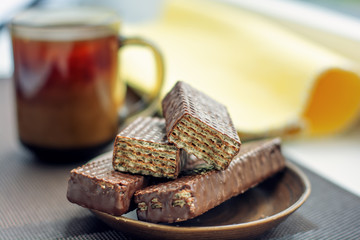 Cup of coffee, chocolate waffles with yellow napkin