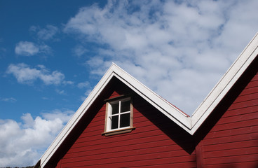 Red wall and roof of a house. One window with white details.