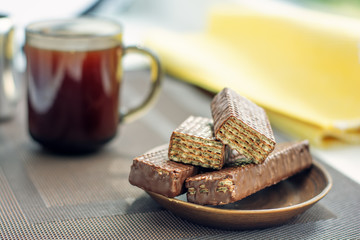Cup of coffee, chocolate waffles with yellow napkin