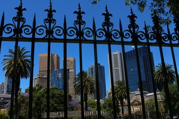 View from Parliament Gardens on skyscrapers in Melbourne through wrought-iron fence