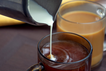 Two cup of coffee. Pouring milk in coffee cup.