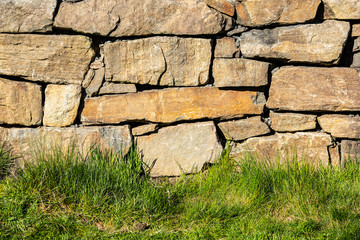 Stone wall behind a grass lawn.