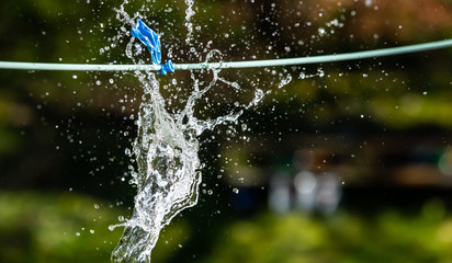 Blue, water-filled balloon on a line. Bursting.