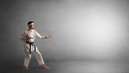 Fototapeta na wymiar Small karate man fighting in an empty grey copy space