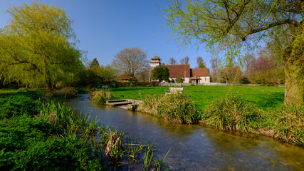 Obraz premium Spring sunshine on St Andrew's Church in Meonstoke in the South Downs National Park, Hampshire, UK