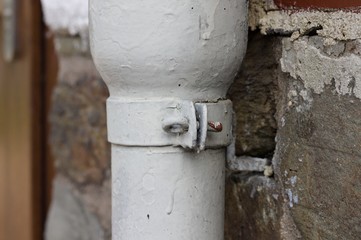 A detail of a screw of a white downpipe (Germany, Europe)