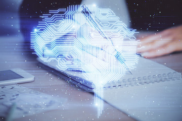 Double exposure of woman's writing hand on background with brain hud. Concept of learning.