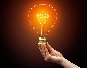 Hand holding light bulb on dark background, new idea concept