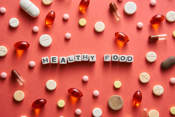 Black-and-white title HEALTHY FOOD from white cubes on the table with tablets on coral background