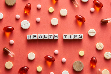 Black and white title HEALTH TIPS from white cubes on the table with tablets on coral background