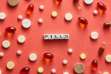 Black and white title PILLS from white cubes on the table with tablets on coral background