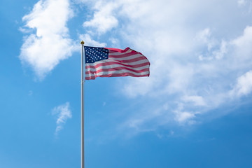 American Flag against Blue Sky with white clouds. American flag fluttering in wind. Independence Day USA. 
